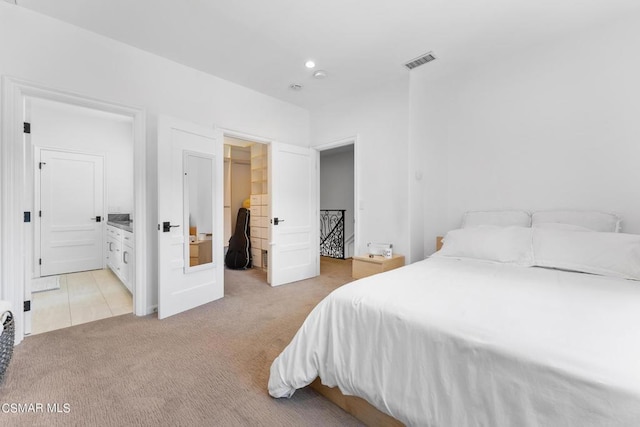 bedroom with a walk in closet, ensuite bathroom, a closet, and light colored carpet