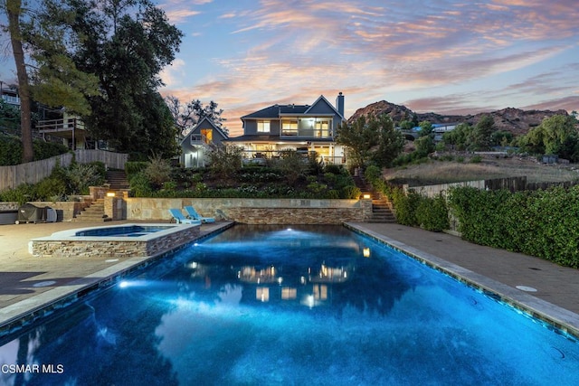 pool at dusk featuring an in ground hot tub and a mountain view