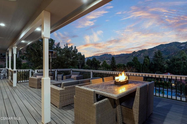 deck at dusk with outdoor lounge area and a mountain view