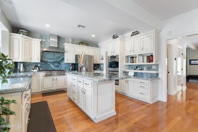 kitchen with white cabinets, wall chimney exhaust hood, a kitchen island, and light wood-type flooring