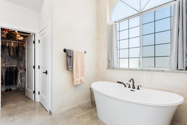 bathroom featuring a bath and tile walls