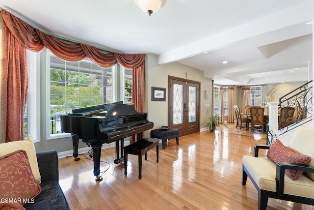 misc room featuring a healthy amount of sunlight, french doors, beam ceiling, and light hardwood / wood-style flooring