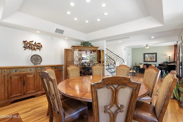 dining room featuring a tray ceiling and light hardwood / wood-style flooring