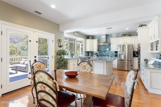 dining room with sink, light hardwood / wood-style floors, and french doors