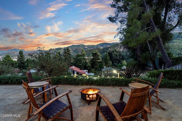 patio terrace at dusk featuring a mountain view and an outdoor fire pit