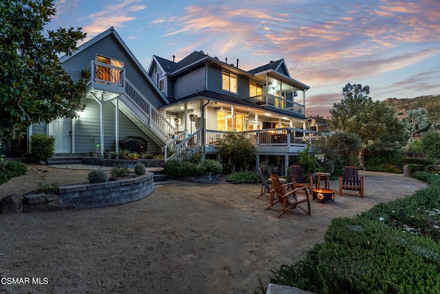 back house at dusk with a balcony and an outdoor fire pit