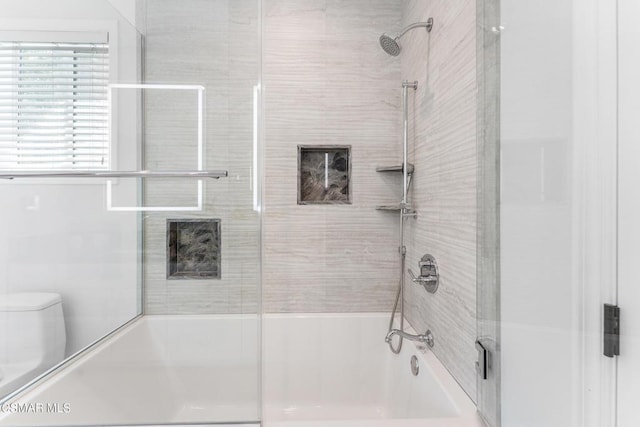 bathroom with toilet and combined bath / shower with glass door