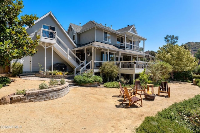 rear view of house with a balcony and a porch