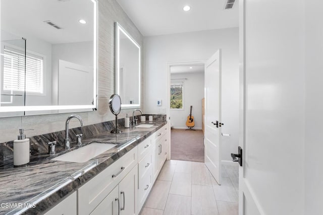 kitchen with white cabinets, light tile patterned flooring, sink, and dark stone counters