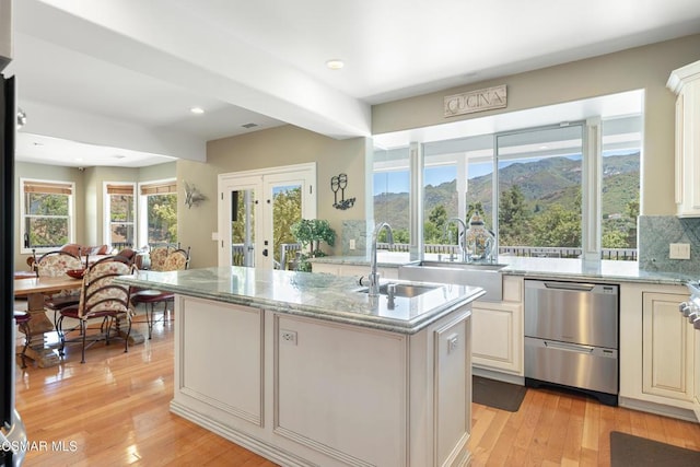 kitchen featuring light stone counters, a center island with sink, and light hardwood / wood-style flooring