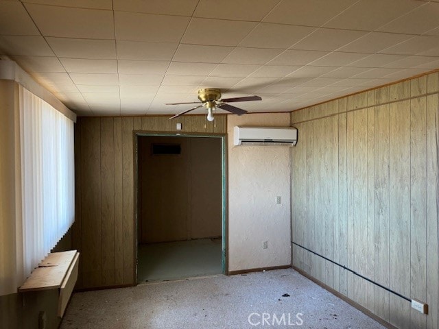 unfurnished room with a wall mounted AC, ceiling fan, and wood walls