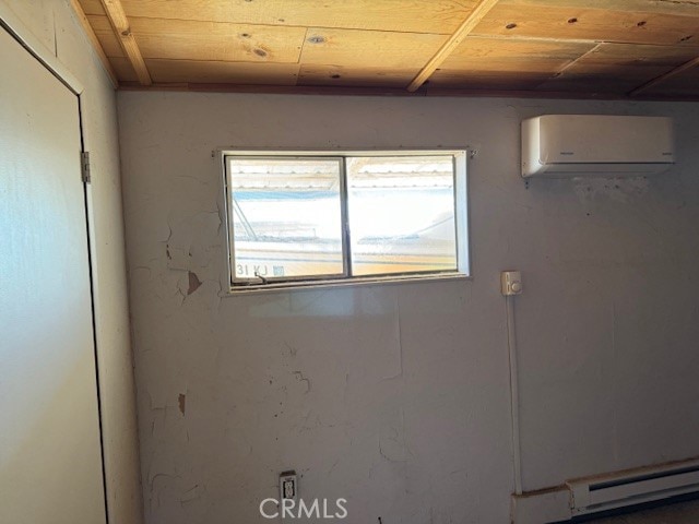 basement with a wall mounted air conditioner, wood ceiling, and baseboard heating