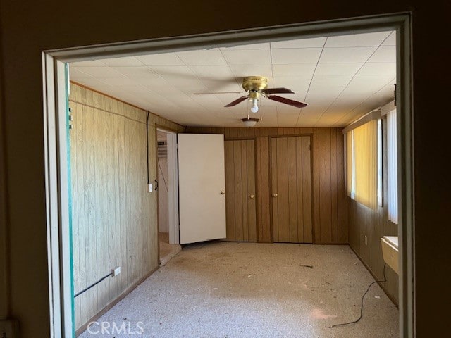 unfurnished bedroom featuring ceiling fan and wood walls