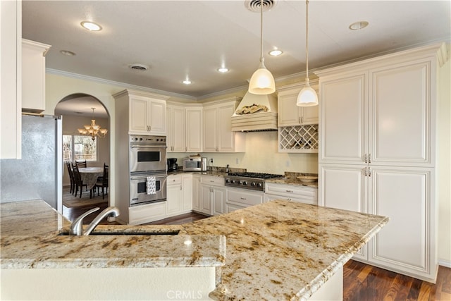 kitchen with light stone countertops, stainless steel appliances, pendant lighting, crown molding, and dark hardwood / wood-style floors