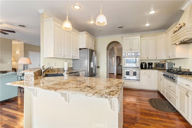 kitchen with appliances with stainless steel finishes, dark wood-type flooring, sink, and hanging light fixtures