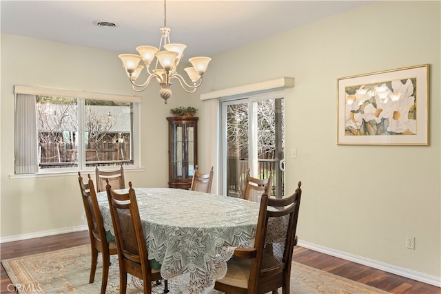 dining space featuring dark wood-type flooring and a chandelier