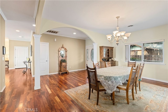 dining room with ornamental molding, a notable chandelier, dark hardwood / wood-style floors, and decorative columns