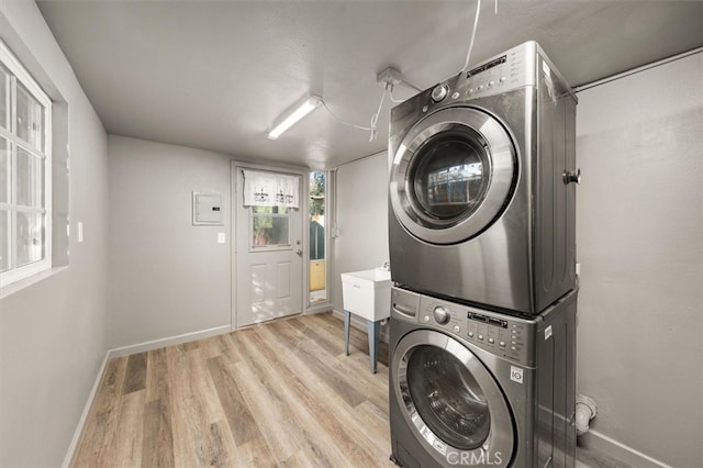 laundry room with light hardwood / wood-style floors, stacked washer and dryer, and sink