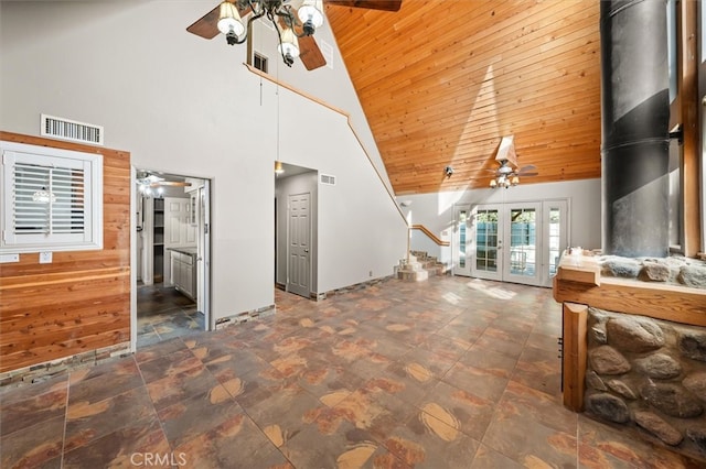 unfurnished living room featuring wooden walls, wood ceiling, high vaulted ceiling, and french doors