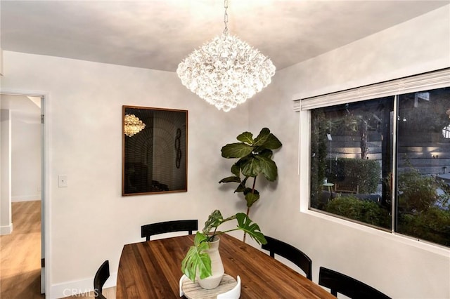 dining space with hardwood / wood-style flooring and an inviting chandelier