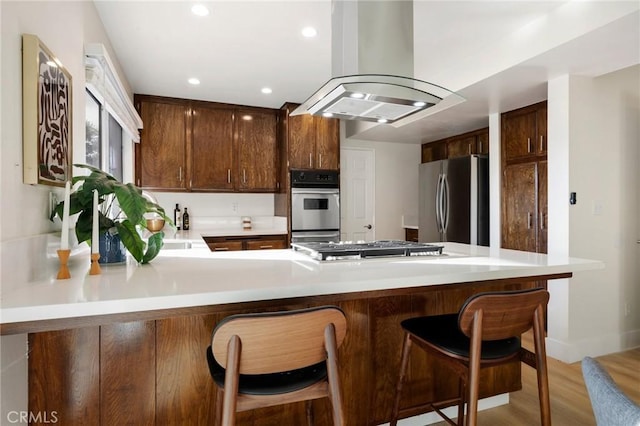 7385 Darnoch Way, West Hills, CA 91307 - kitchen featuring appliances with stainless steel finishes, island exhaust hood, a peninsula, light wood finished floors, and light countertops