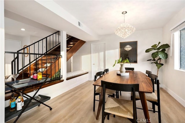 dining space with light hardwood / wood-style flooring and an inviting chandelier