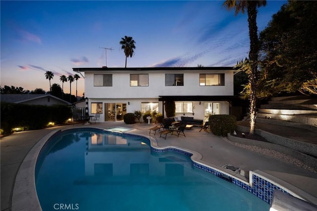 pool at dusk with an outdoor living space and a patio