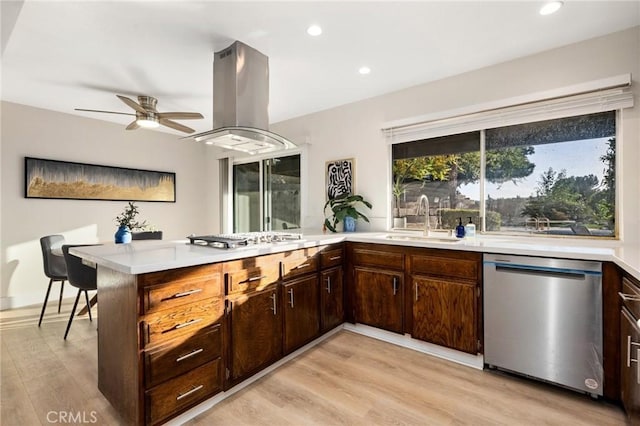 kitchen with sink, light hardwood / wood-style flooring, island range hood, kitchen peninsula, and stainless steel appliances