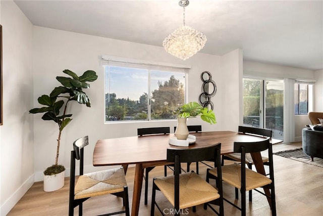 dining space with a chandelier, light hardwood / wood-style floors, and a healthy amount of sunlight