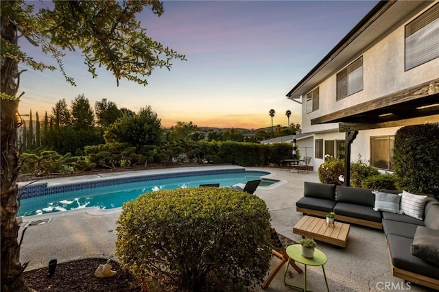 pool at dusk featuring an outdoor hangout area and a patio