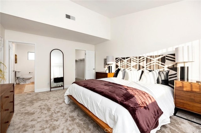 carpeted bedroom with ensuite bath, a spacious closet, and a closet