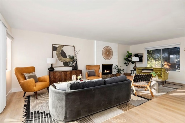 living room with a brick fireplace, a healthy amount of sunlight, and light hardwood / wood-style flooring