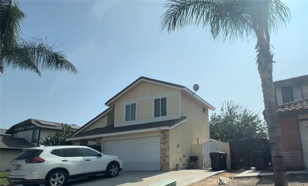 17251 Walnut Ave, Fontana, CA 92336 - view of front facade featuring stone siding, an attached garage, a gate, stucco siding, and driveway