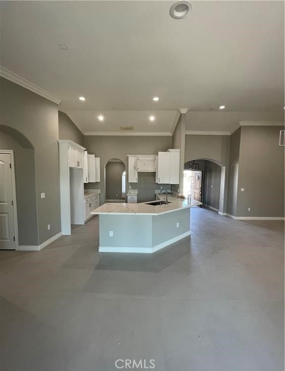 kitchen featuring a center island with sink, ornamental molding, sink, and white cabinets