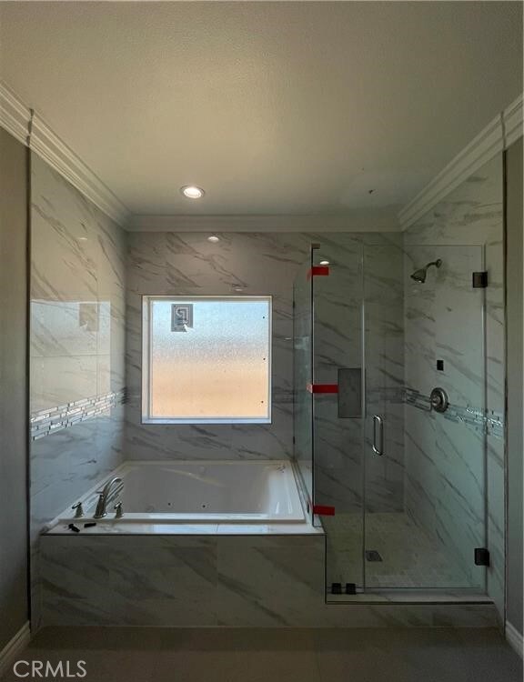 bathroom featuring ornamental molding and shower with separate bathtub