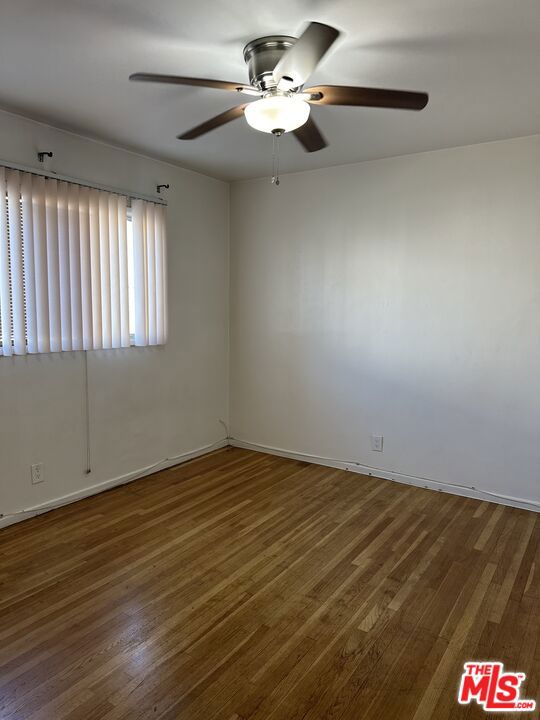 spare room with dark wood-type flooring and ceiling fan