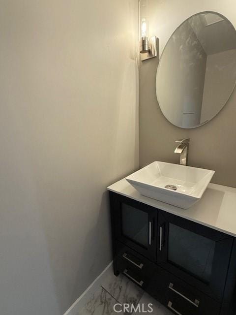 bathroom with vanity, marble finish floor, and baseboards