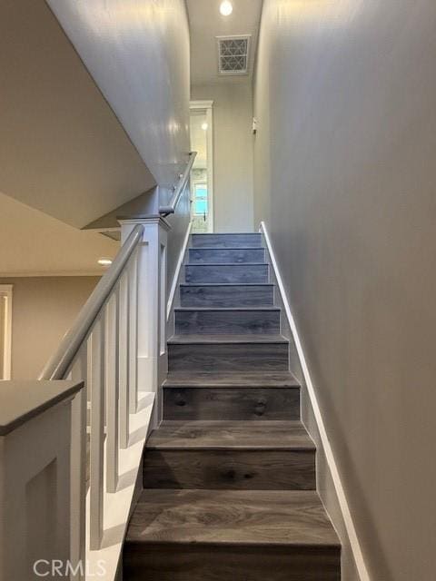 stairs with wood finished floors and visible vents