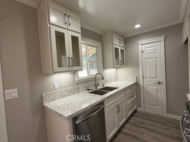 kitchen featuring a sink, dishwasher, glass insert cabinets, and ornamental molding