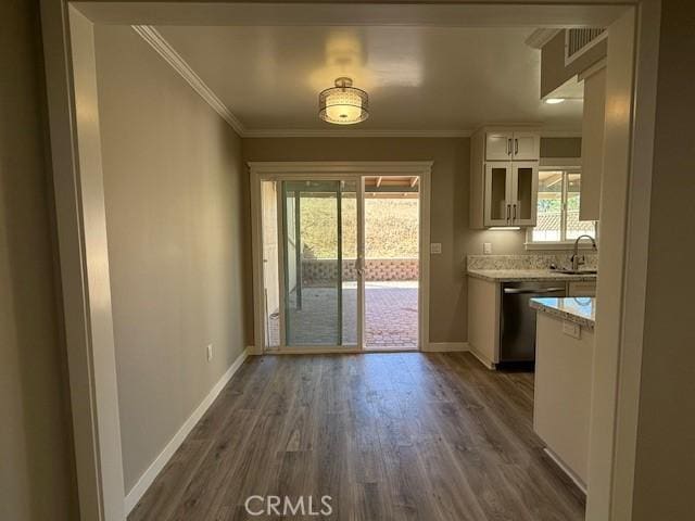 unfurnished dining area with baseboards, a sink, dark wood finished floors, and ornamental molding