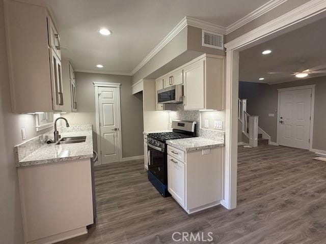 kitchen featuring visible vents, a sink, baseboards, stainless steel microwave, and range with gas stovetop