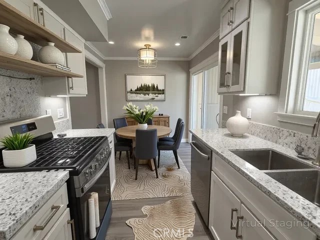 kitchen with ornamental molding, wood finished floors, recessed lighting, a sink, and stainless steel appliances