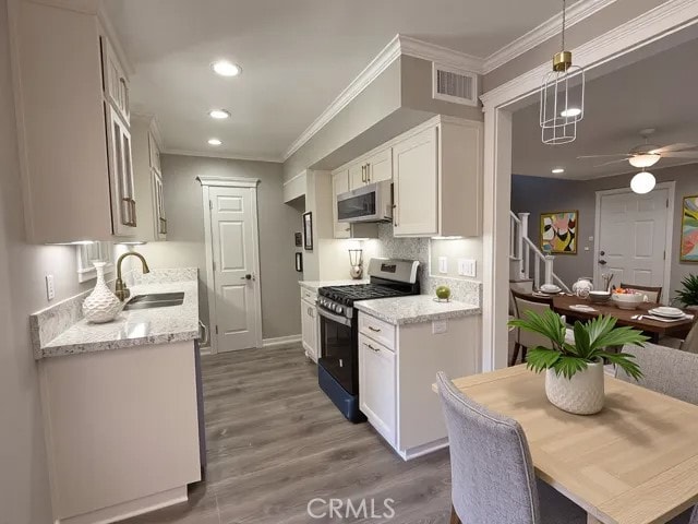 kitchen featuring ceiling fan, appliances with stainless steel finishes, ornamental molding, and a sink