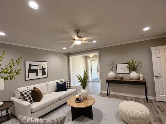 living area with recessed lighting, ornamental molding, a ceiling fan, and wood finished floors