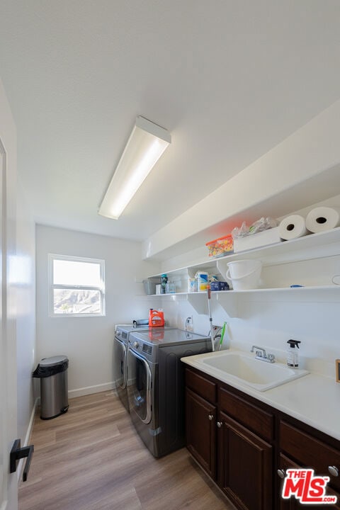 laundry area with cabinets, sink, independent washer and dryer, and light hardwood / wood-style flooring