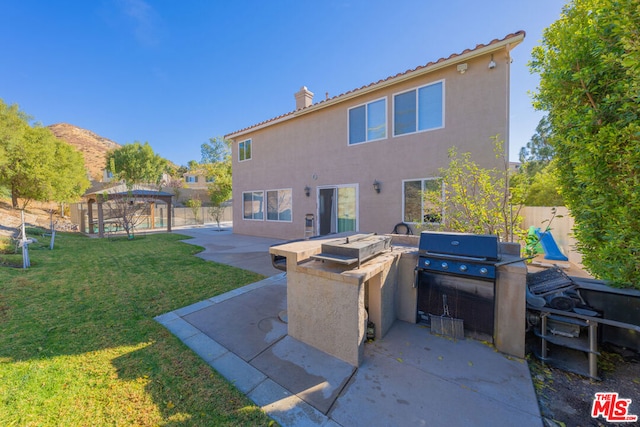 back of property with a patio area, a mountain view, a yard, a gazebo, and an outdoor kitchen