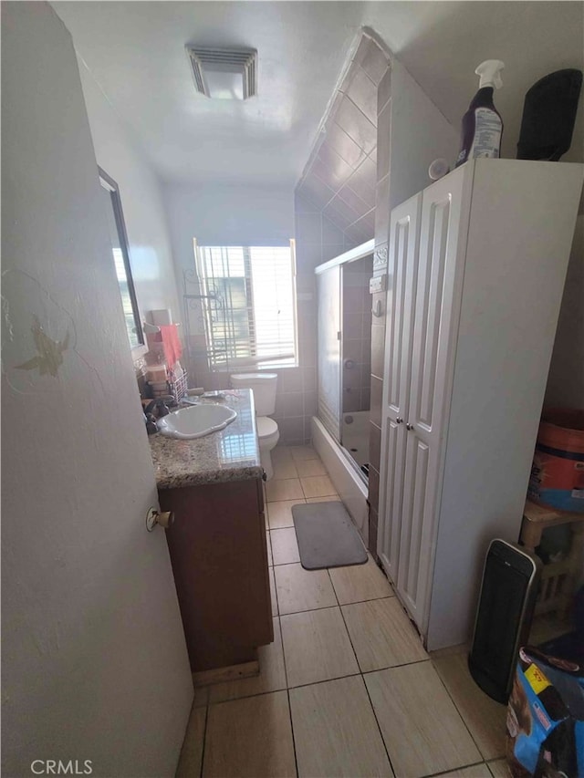 bathroom with toilet, tile patterned flooring, vanity, tile walls, and an enclosed shower