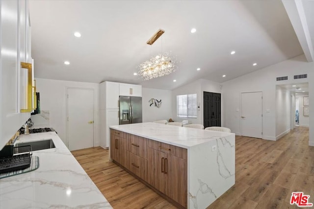 kitchen with lofted ceiling, white cabinets, stainless steel refrigerator with ice dispenser, and light hardwood / wood-style flooring