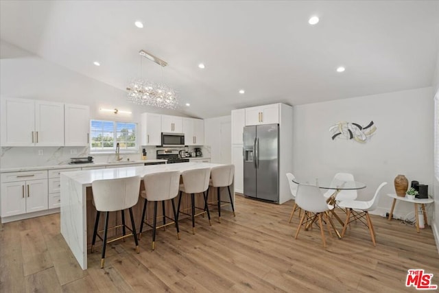 kitchen featuring appliances with stainless steel finishes, light hardwood / wood-style flooring, white cabinetry, and an island with sink