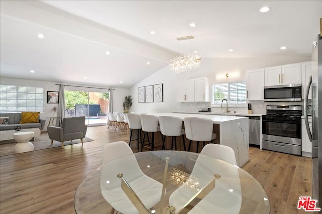 kitchen featuring decorative light fixtures, vaulted ceiling with beams, stainless steel appliances, and a healthy amount of sunlight